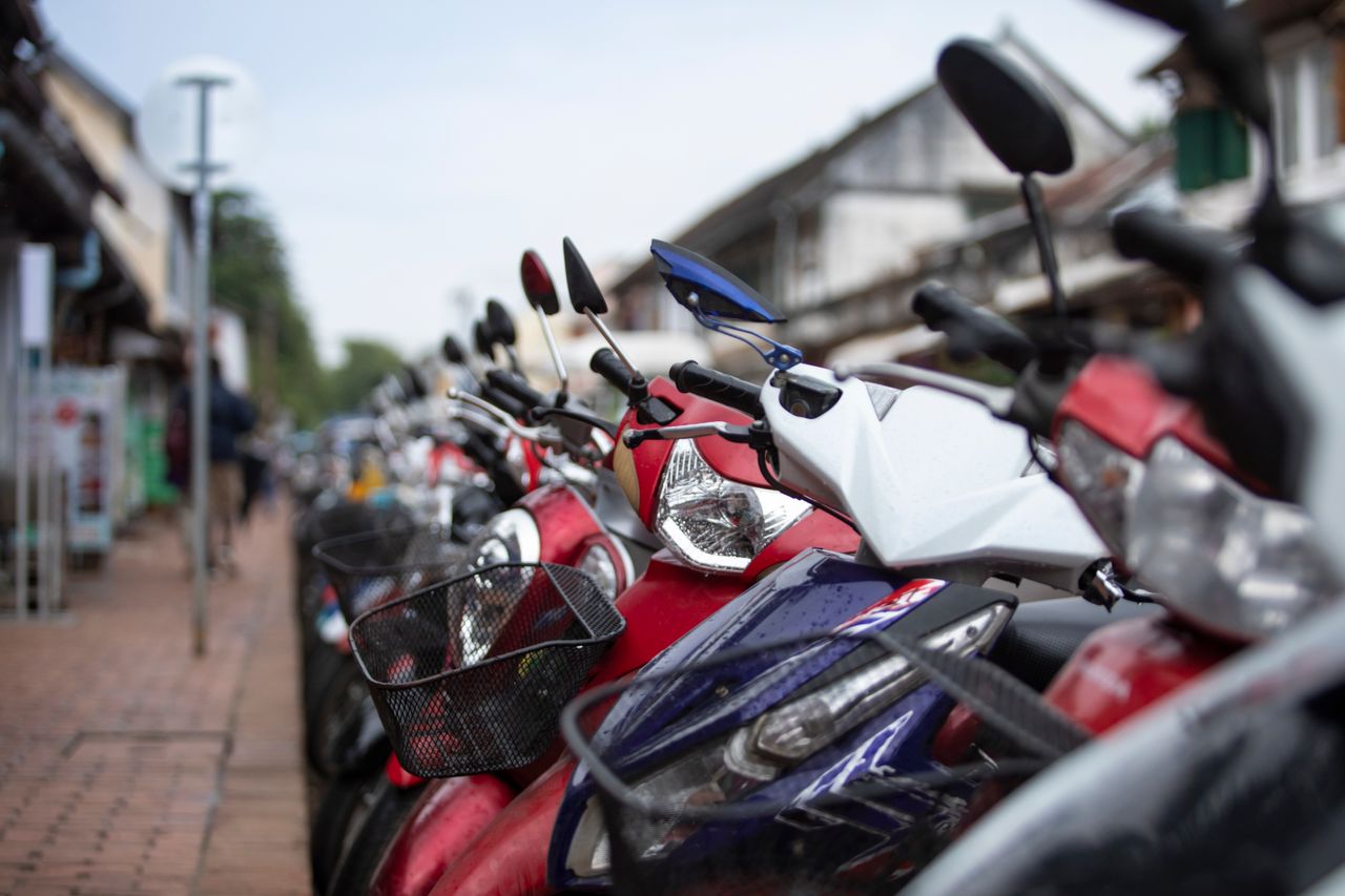 Close-up of multiple scooters parked on a rainy city street. Urban transportation scene.