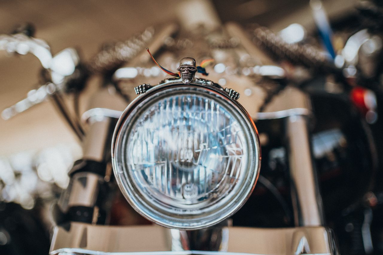 Detailed image of a motorcycle headlight adorned with a skull ornament, showcasing biker culture.