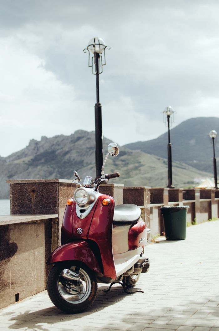 Vintage scooter parked on coastal promenade with mountain backdrop in Simferopol.
